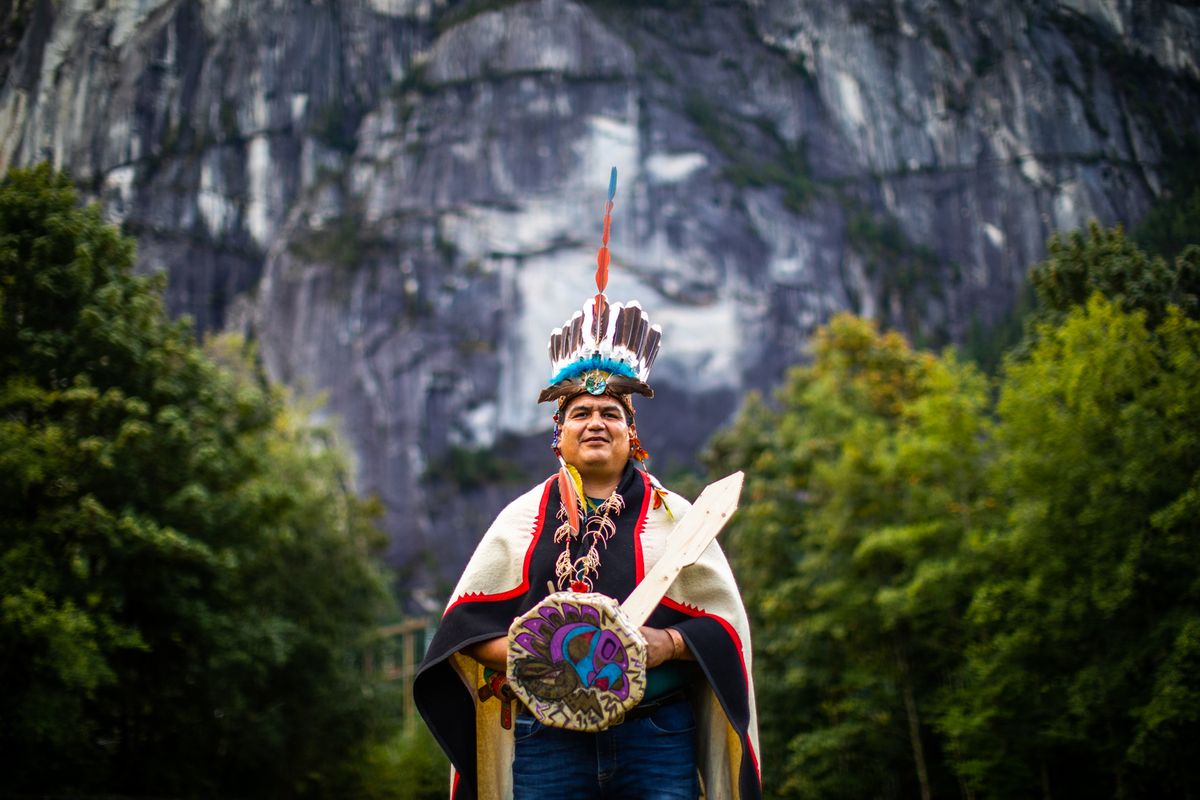 Portrait in traditional regalia beneath the granite walls of Squamish