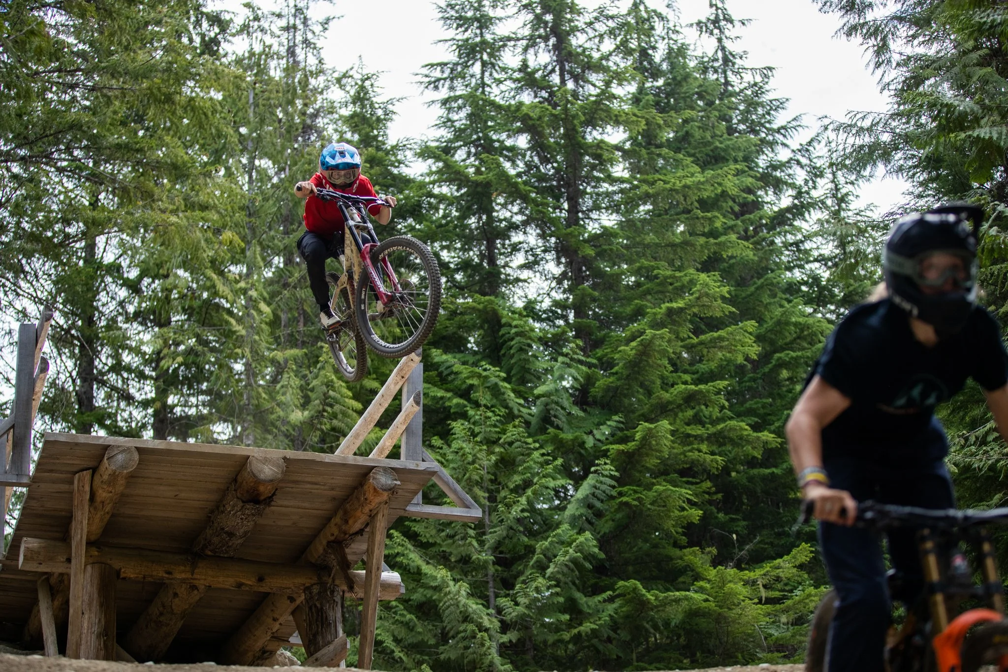 Casey Brown launching off natural jump on mountain bike trail