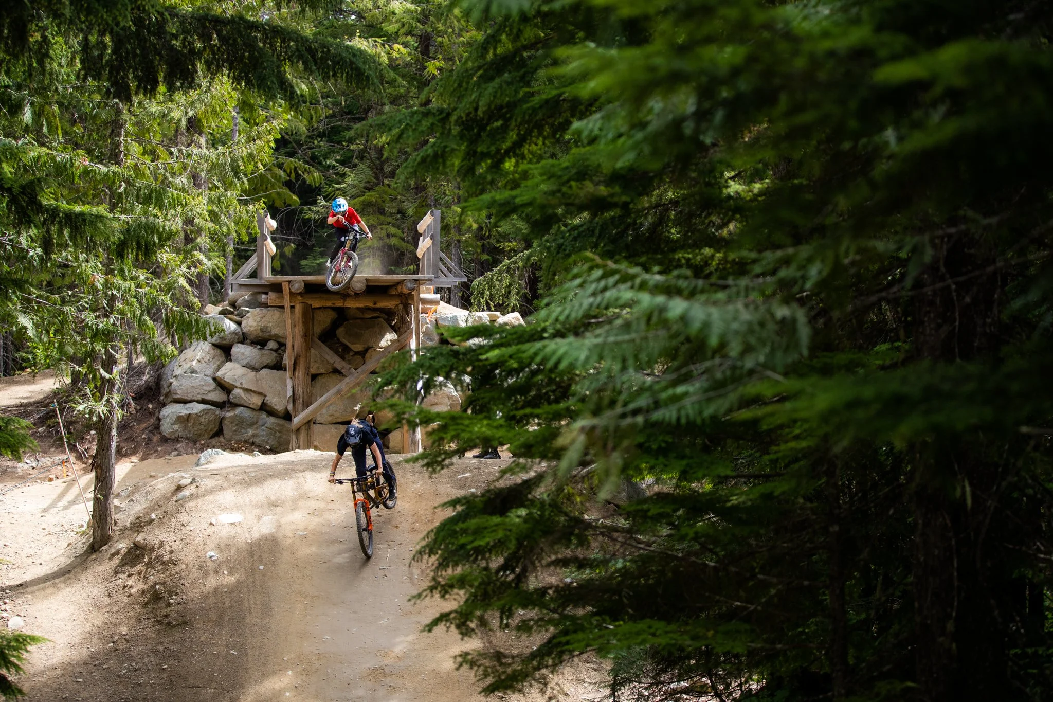 Mountain biker dropping off rock feature with mountain views behind